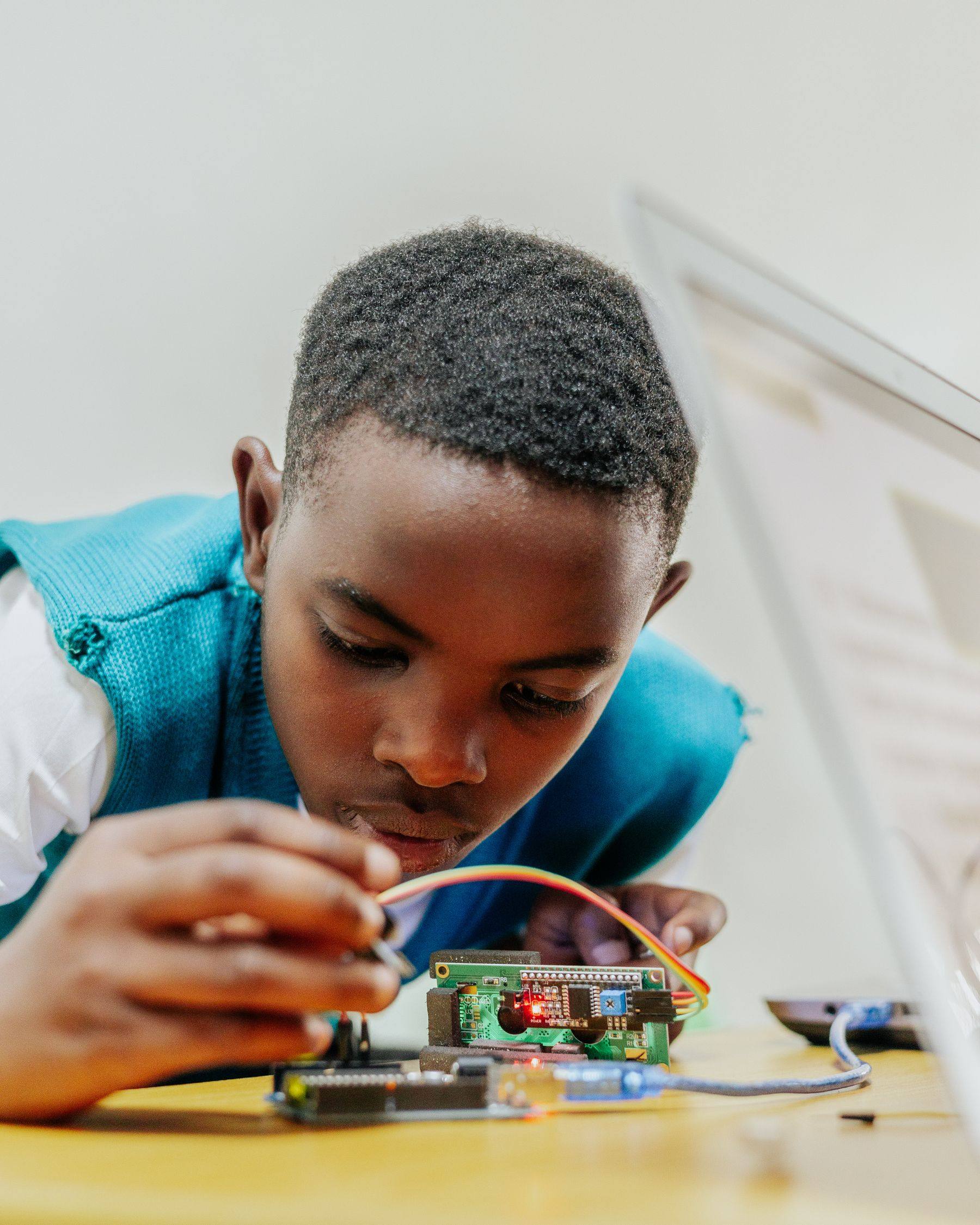A boy concentrates as he connects wires to a circuit board.